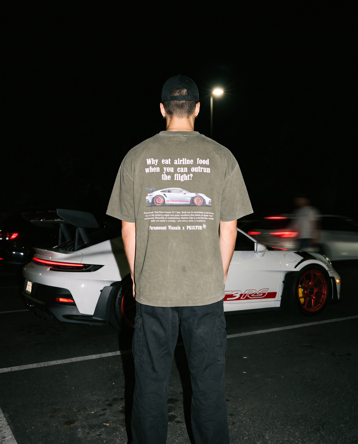 Olive Green Flight Shirt Back Male_paramountvisuals x porsche kultur standing in front of a Porsche 911 GT3RS